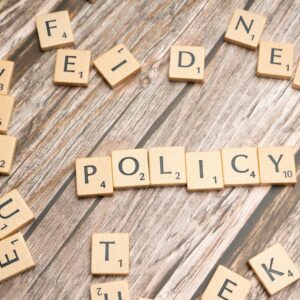 Scrabble letter tiles on a wooden background forming the word "Policy".